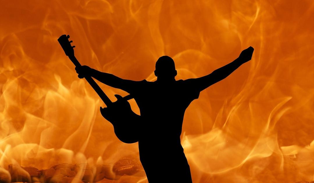 a fire background with a rock band guitar player at the center